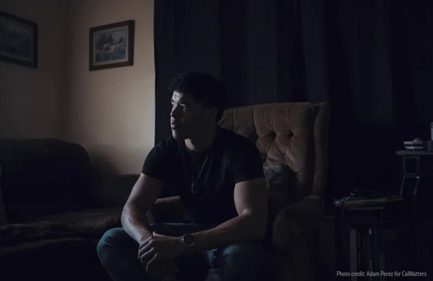 young man sitting on couch in a dark room