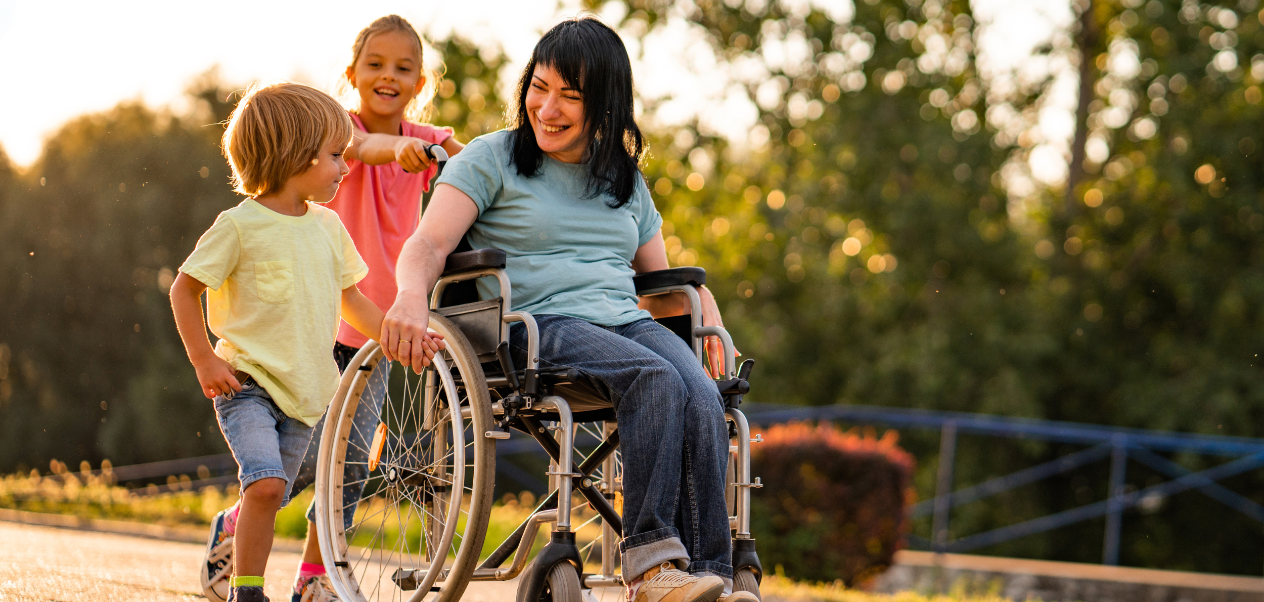 Woman in a wheelchair in nature with two children.