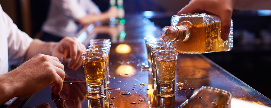 Bartender pouring shots for a customer at a bar