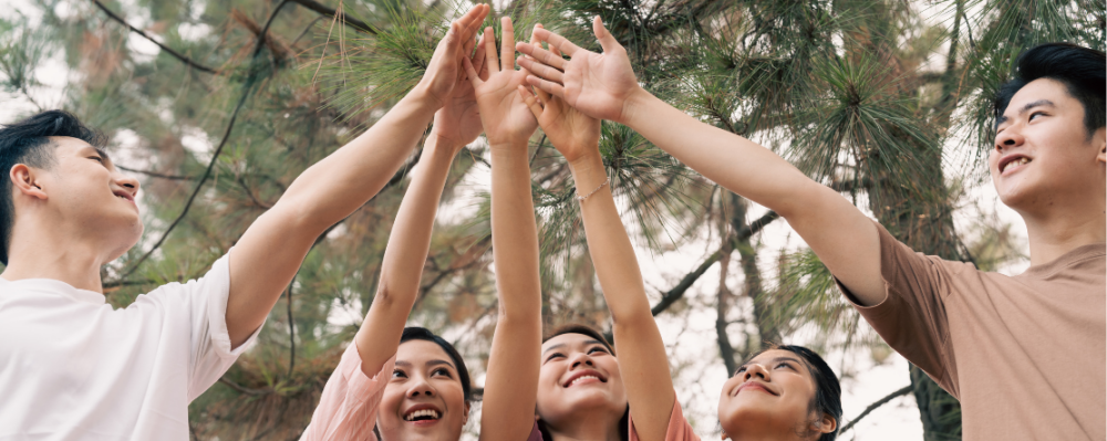 Asian teens with hands in a huddle