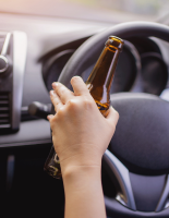 person driving holding beer bottle