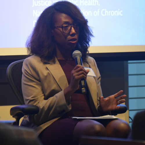 Woman holding a microphone and presenting at a meeting