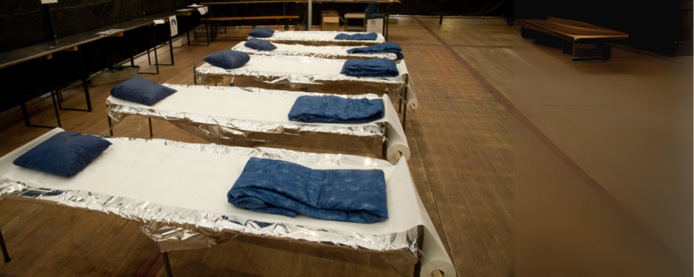 Emergency cots lined up in disaster relief shelter