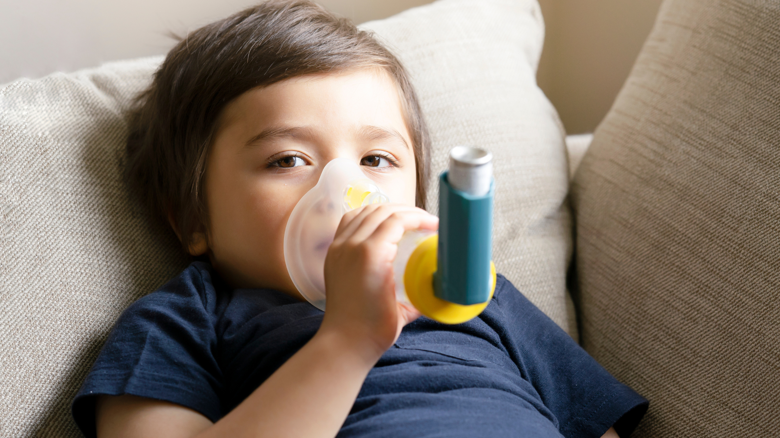 Child, lying on a couch and using an inhaler