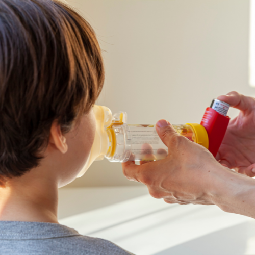 person helping child use inhaler