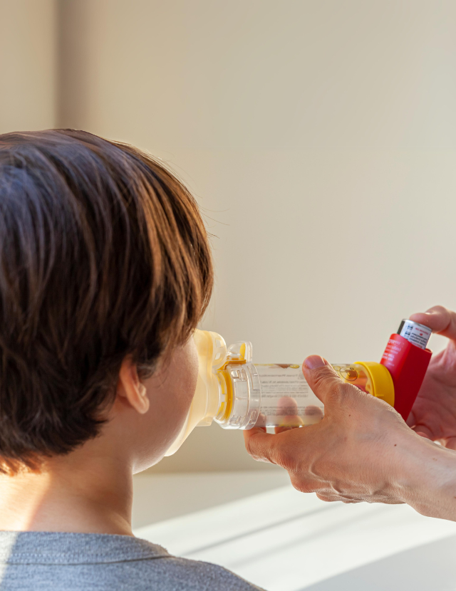 person helping child use inhaler