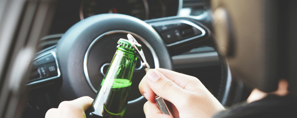 person is opening a bottle of alcohol while in the car