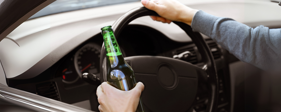 person holding beer bottle while driving