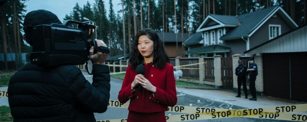 reporter and camera person stand in front of crime scene