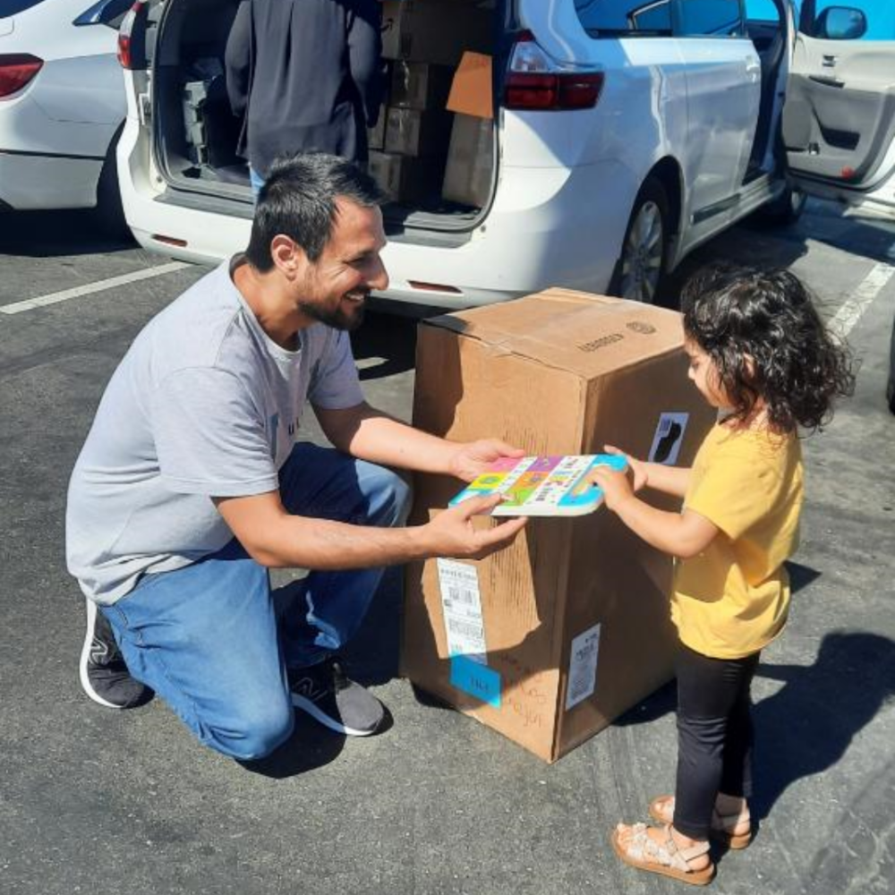 Sediq giving a book to child