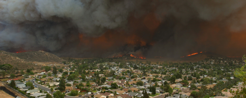 neighborhood with wildfire and smoke in the background