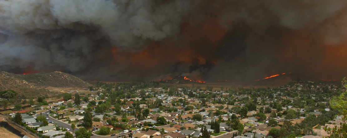 neighborhood with wildfire and smoke in the background