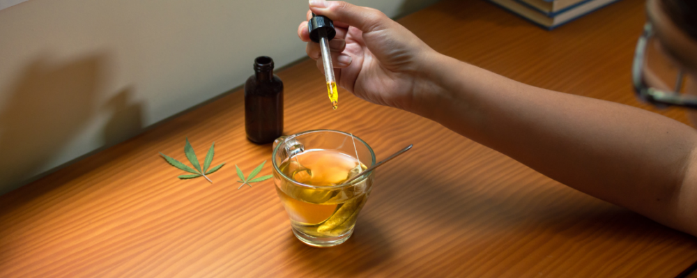 person adding cannabis drops to beverage